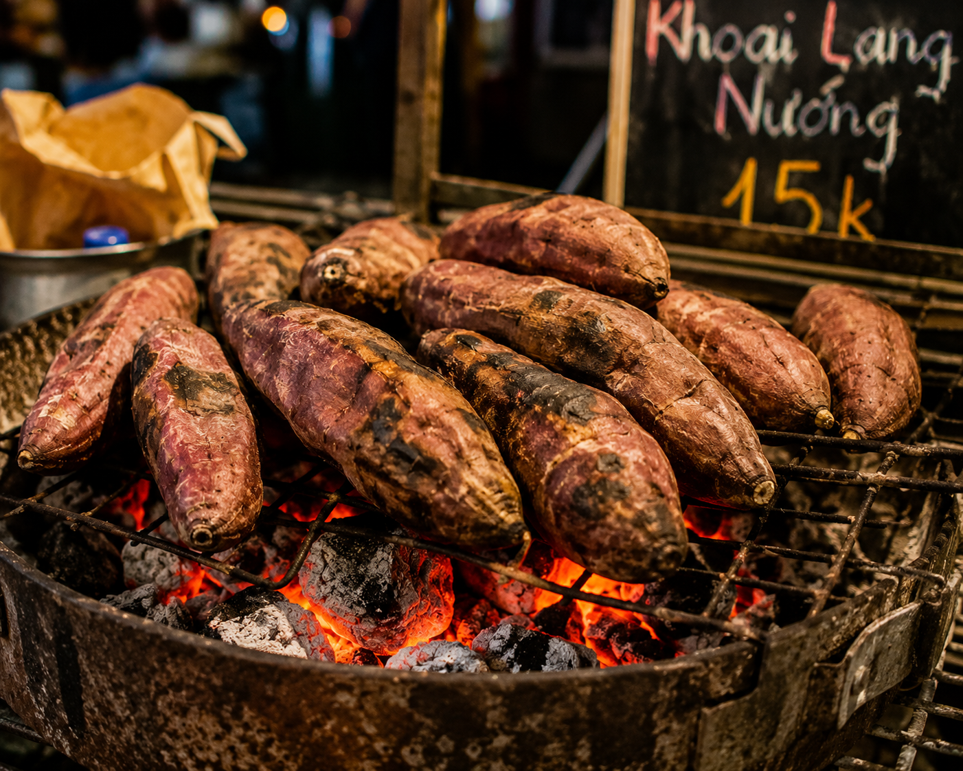 Khoai lang nướng roasted sweet potatoes cooking over charcoal in Vietnam