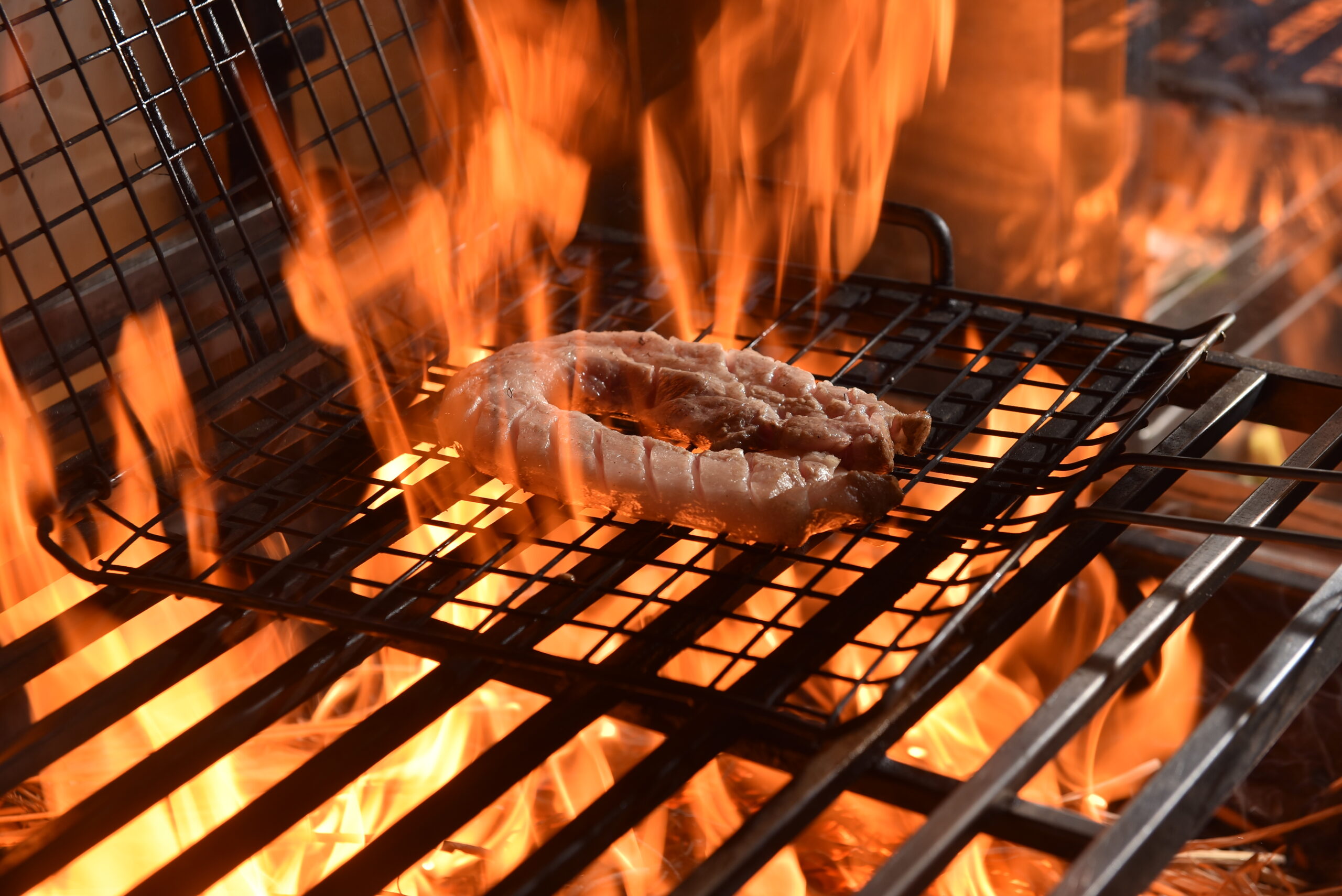 Straw-fired Korean BBQ pork grilling over flames at Nướng Rơm in Da Nang