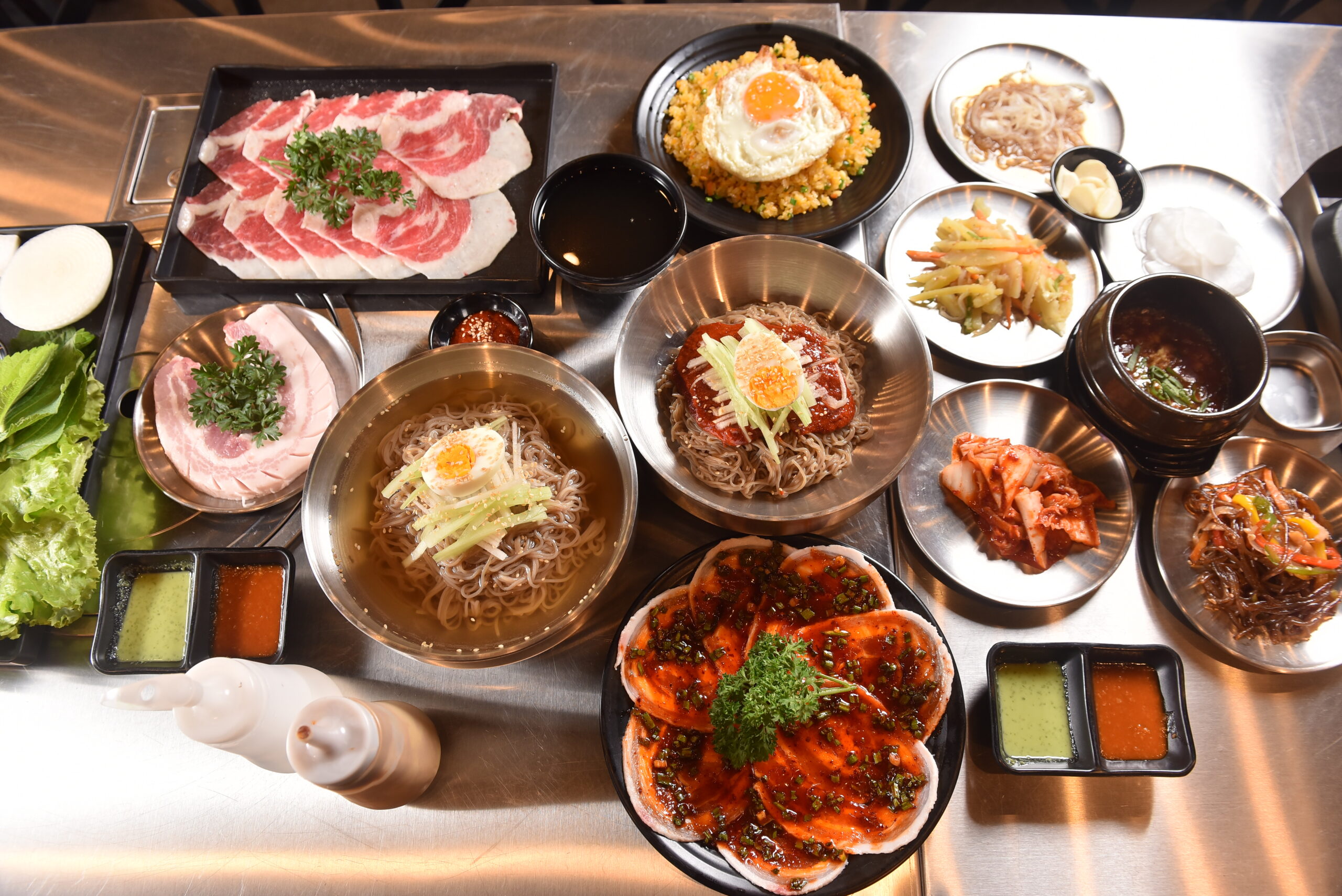 Korean BBQ set with pork noodles kimchi and side dishes at Nuong Rom Da Nang